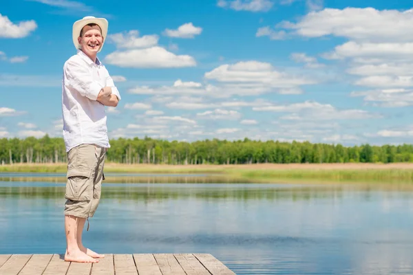 Portret van een gelukkig man in volle lengte op een houten pier op de b — Stockfoto