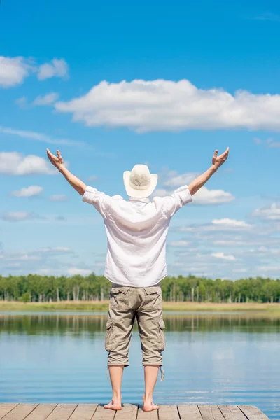 The man on the pier with his arms stretched out to the sides enj — Stock Photo, Image