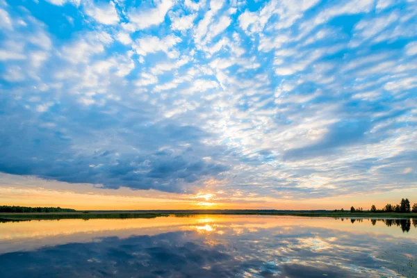 Nuvens bonitas sobre um lago pitoresco, sol laranja ao amanhecer — Fotografia de Stock