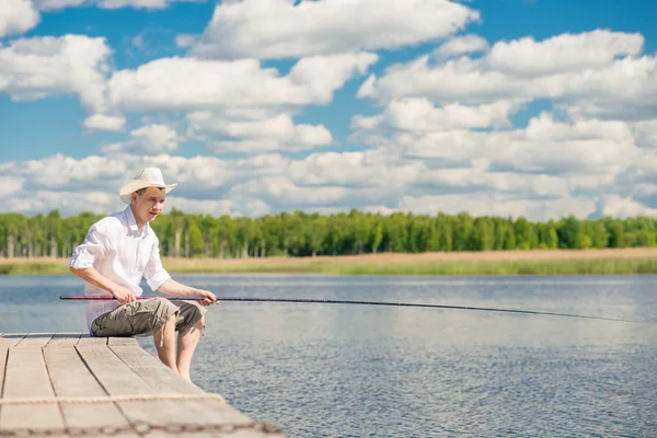 Portrait of a fisherman in a hat on a wooden pier on a beautiful — Stock Photo, Image