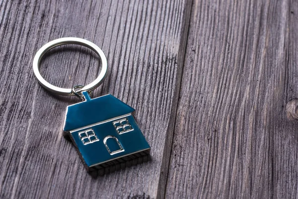 Porte-clés en acier avec une photo d'une maison sur une table en bois — Photo