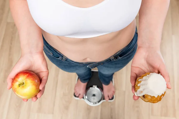 Концепция выбора и потери веса, женщина на весах с приложением — стоковое фото