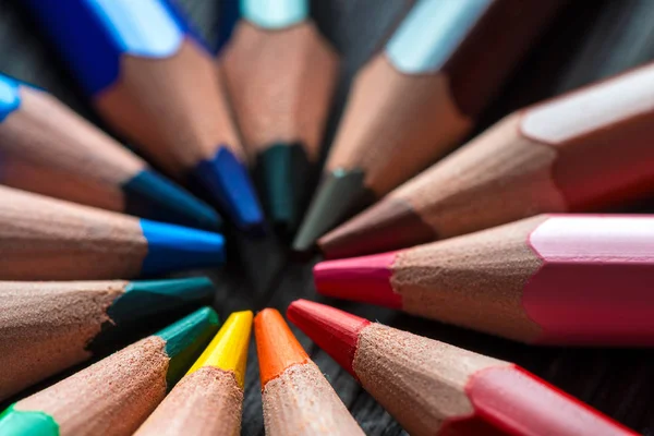 Colored pencils in the center of the table lie in a circle — Stock Photo, Image