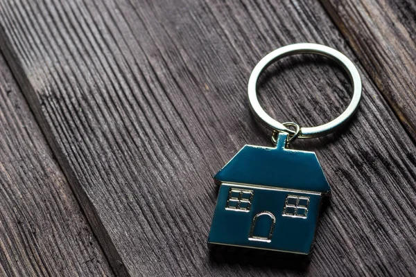 Keychain in the shape of a house on wooden boards close-up — 스톡 사진