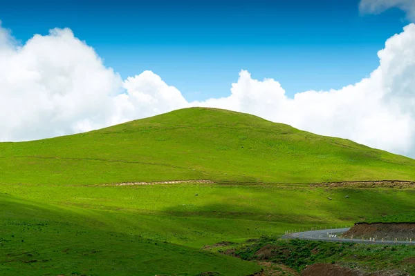 Pintoresca colina verde sobre un fondo de cielo azul en un claro su — Foto de Stock