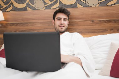 Otel odasında üzerinde sörf beyaz elbise içinde çekici genç adam 