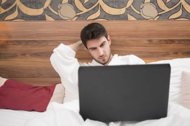 Otel odasında üzerinde sörf beyaz elbise içinde çekici genç adam 