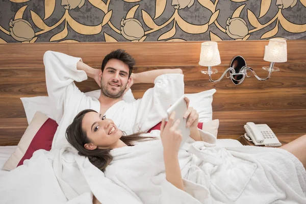 Hermosa joven pareja feliz disfrutando en la cama después del spa. Pareja i — Foto de Stock