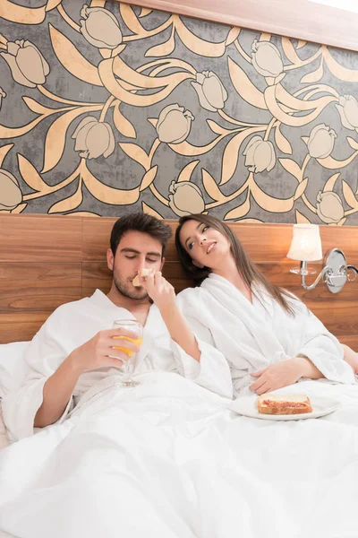 Atractiva pareja joven con túnicas blancas, disfrutando de la comida y la bebida — Foto de Stock
