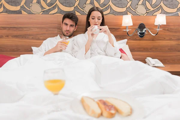 Atractiva pareja joven con túnicas blancas, disfrutando de la comida y la bebida — Foto de Stock