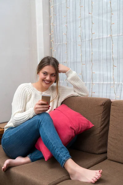 Mujer joven sentada en el sofá y usando el teléfono inteligente celular en mountai — Foto de Stock