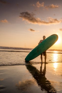 Sahilde sörf tahtası olan bir sörfçü.