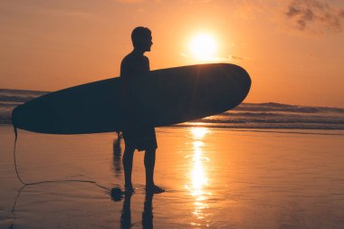 Sahilde sörf tahtası olan bir sörfçü.