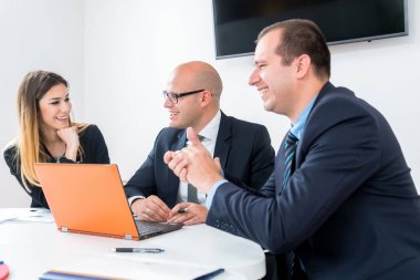 Üç ofisinde oturan ve iş planlama bir iş takımı. İş stratejisi yapmak dizüstü bilgisayar kullanarak. Başlangıç geliştirme.