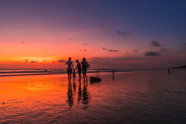 Praia com pessoas ao pôr do sol — Fotografia de Stock