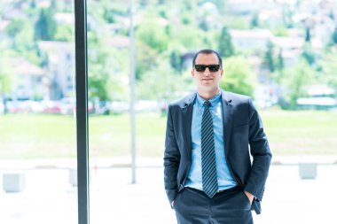 ofisinde bir güneş gözlüklü bir iş adam portresi. Kendine güvenen iş adam, ceo, sahibi pencerenin önünde modern ofisinde.