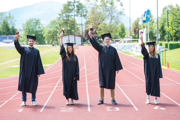 Maturitní parta studentů slaví na atletické dráze s — Stock fotografie