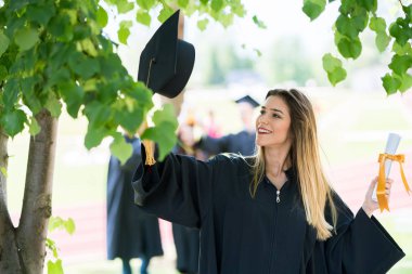 Mezuniyet: Öğrenci arkadaşlar arkasında diplomasıyla ile ayakta