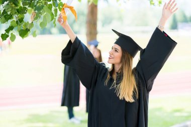 Mezuniyet: Öğrenci arkadaşlar arkasında diplomasıyla ile ayakta