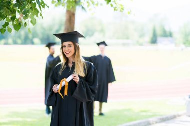 Mezuniyet: Öğrenci arkadaşlar arkasında diplomasıyla ile ayakta