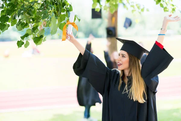 Afstuderen: Student permanent met Diploma met vrienden achter — Stockfoto