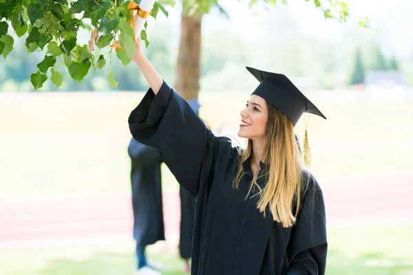 Graduación: Estudiante de pie con diploma con amigos detrás —  Fotos de Stock