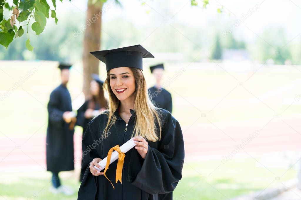 Graduation: Student Standing With Diploma With Friends Behind