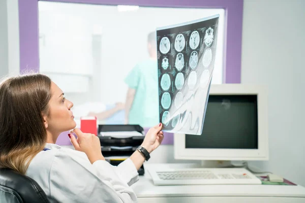 Doctora mirando una radiografía en su consultorio — Foto de Stock