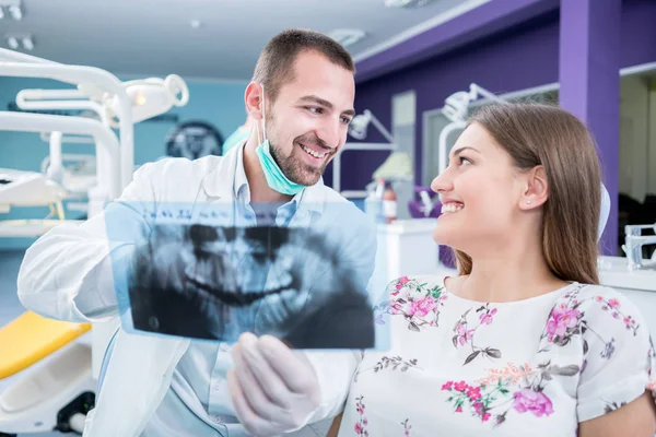 Врач разговаривает с пациентом и показывает рентген в стоматоле — стоковое фото