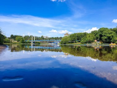 Yaroslavl'daki Kotorosl nehri üzerinde kablolu köprü kaldı. Damansky adasından manzara. Güzel yaz günü; su yüzeyinde sahil ve köprü yansıması
