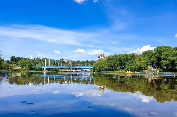 Yaroslavl'daki Kotorosl nehri üzerinde kablolu köprü kaldı. Damansky adasından manzara. Güzel yaz günü; su yüzeyinde sahil ve köprü yansıması