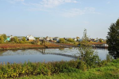 Rusya 'nın kuzeyinde sonbahar. Shikhirikha Arkhangelsk bölgesindeki asma köprü. Olağanüstü perspektif ve simetri. Malkurya Nehri