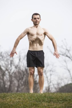 Karın gerçekleştirme adam ayakta çimenlerin üzerinde egzersiz