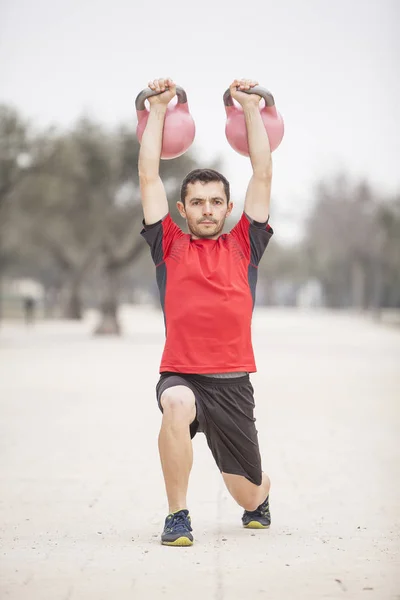 man training with kettle bells in the park