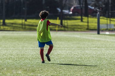 Antrenman önlüklü tanınmayan genç futbolcu, antrenmandan önce ısınıyor.