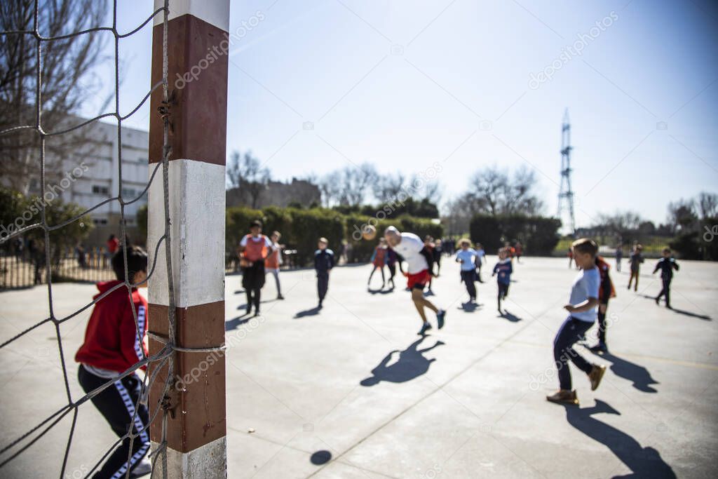 unfocused image of playground in a school, unrecognizable children playing soccer