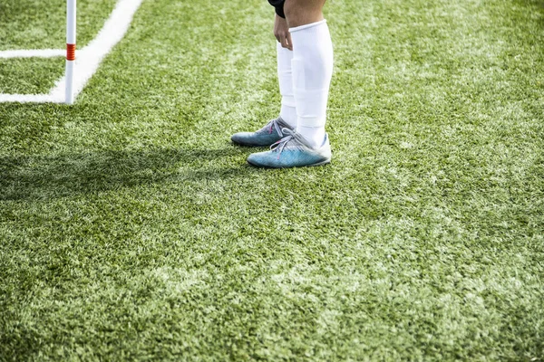 Genç ve tanınmayan futbolcu oynamak için ısınıyor. Oyun sahasındaki bacakları görüyor.