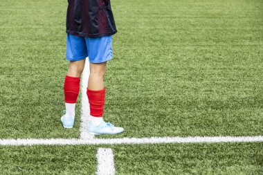 Genç ve tanınmayan futbolcu oynamak için ısınıyor. Oyun sahasındaki bacakları görüyor.