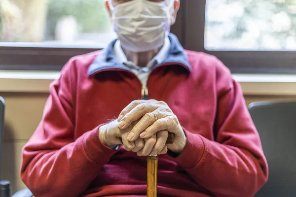 Doktor muayenehanesinde solunum cihazıyla oturan tanınmayan yaşlı bir adam.