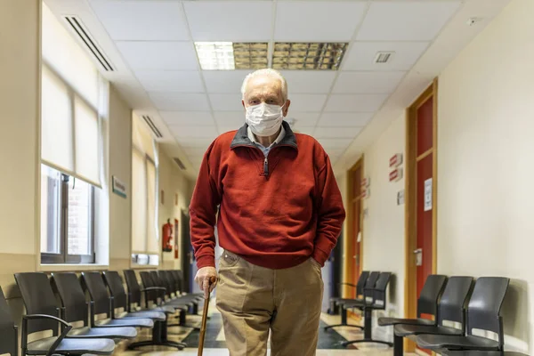 Solunum cihazı olan bir hastanede tıbbi konsültasyon koridorunda yürüyen yaşlı bir adam.