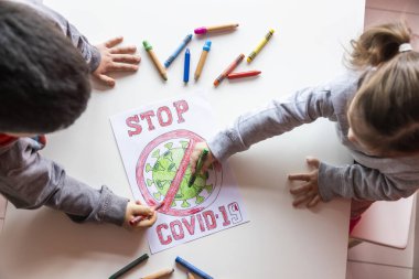 Tanımlanamayan kız ve erkek, beyaz bir masaya Coronavirus 'un resmini çiziyor.