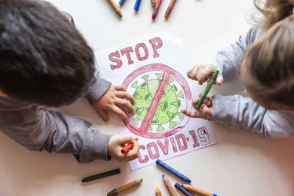 Tanımlanamayan kız ve erkek, beyaz bir masaya Coronavirus 'un resmini çiziyor.