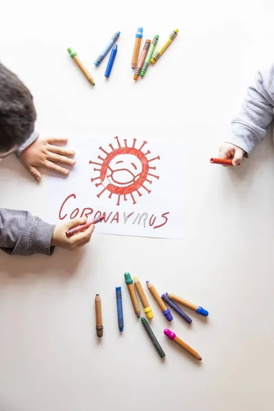Unrecognizable boy and girl color a drawing of stop coronavirus on a white table, top view