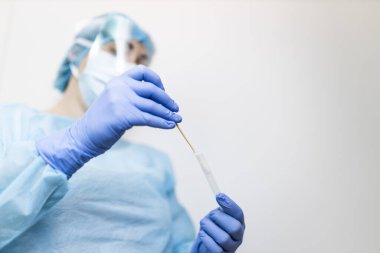 Koruyucu kıyafetli genç hemşire covid-19 testi yapıyor.