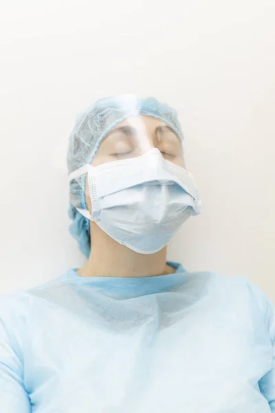 Young nurse in protective clothing resting after a hard shift