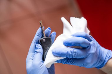 Tanımlanamayan bir kadın evinin yüzeyini dezenfekte ediyor, araba anahtarını dezenfekte ediyor.