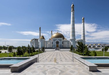 Ashgabat, Turkmenistan - June 1, 2019: The Mosque near masoleum of Turkmenbasy, the president Niazov, in the white and marble city of Asjchabad with great buildings and landmarks in Turkmenistan. clipart