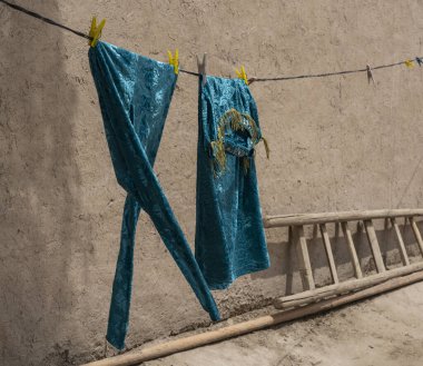 Özbekistan 'ın eski şehir merkezi Khiva' daki çamaşır ipinde rüzgâr giysilerle oynuyor.