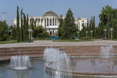 Dushanbe, Tazjikistan - 14 Haziran 2019: Ağaçlı, çeşmeli ve başkenti Dushanbe 'deki büyük binalı Rudaki Parkı.