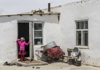 Alichur, Tajikistan - June 24, 2019: Child at the door in small town of Alichur in region Murghob in Gorno-Badakshan  with houses and unpaved roads.